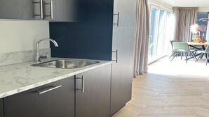 Una cocina moderna con armarios oscuros, encimera de mármol y un lavabo.
