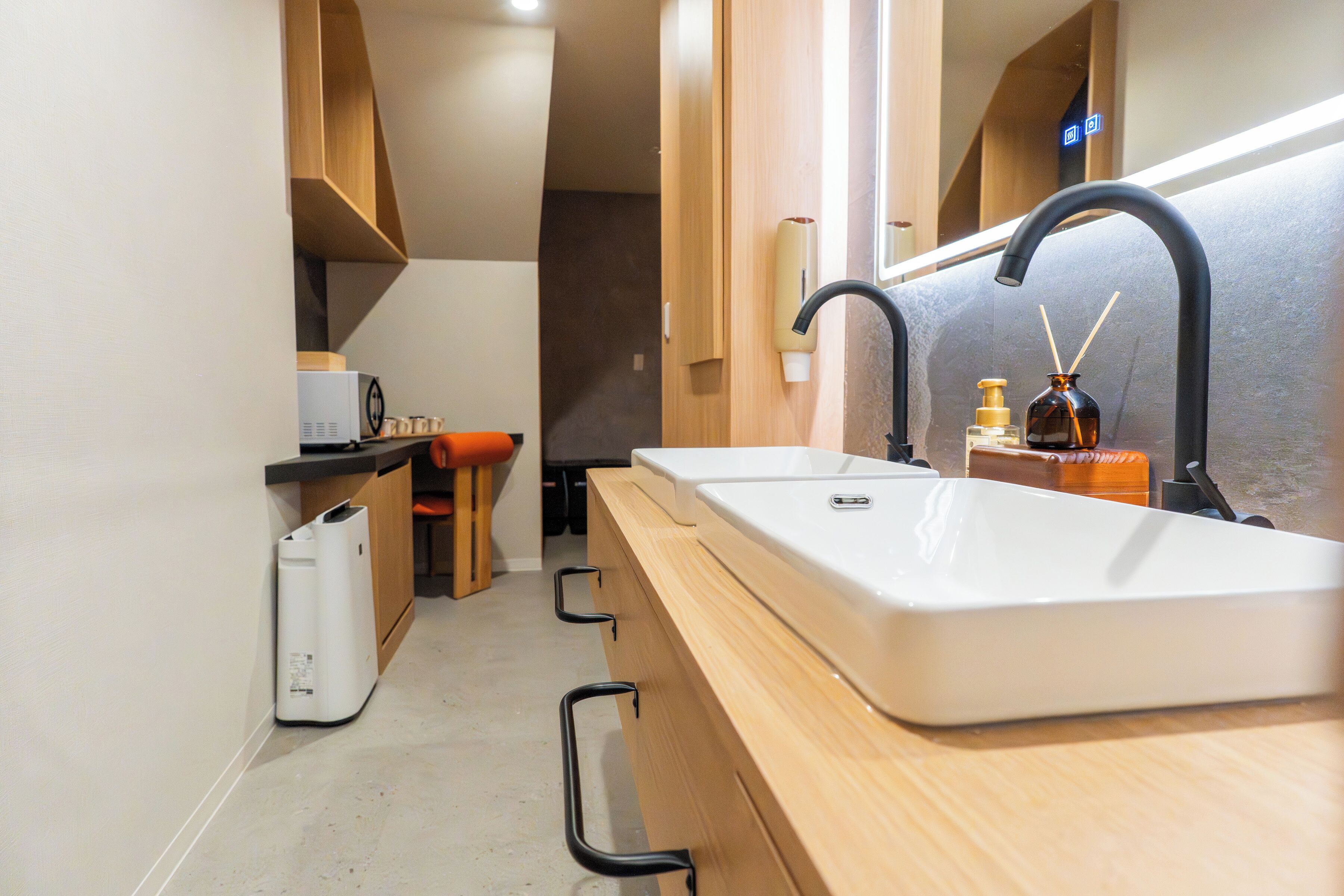 A compact kitchen with a white sink, black faucet, and wooden cabinets.