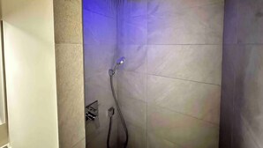 Een moderne douche met een blauwe LED-verlichtingsarmatuur en een handdouche.