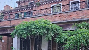 Ein Innenhof mit einem Backsteingebäude, einer Pergola mit Kletterpflanzen und einem Rosengewächs.