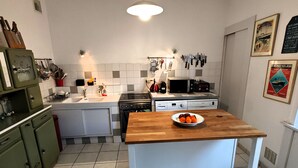 Eine Küche mit einem Holztisch, weißen Schränken, einer Spüle, einem Herd und einer Mikrowelle.