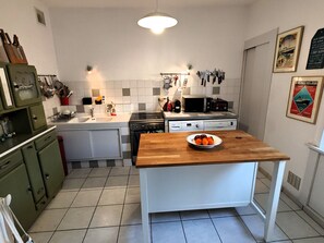 A kitchen with a wooden table, white cabinets, a sink, a stove, and a microwave. - Villa Simone 200m from the Beach (Les Sables-d´Olonne)