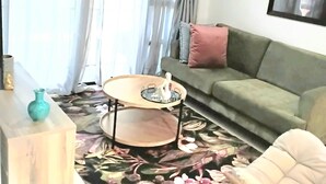 Un salon avec un canapé vert, une table basse ronde et un tableau accroché au mur.
