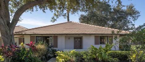 Arrive to a sunlit entrance framed by lush tropical landscaping.