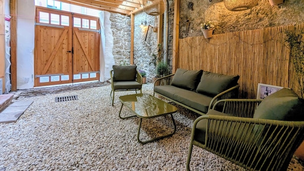 Un intérieur rustique avec un plafond en bois, des murs en pierre, une porte en bois et un canapé vert.