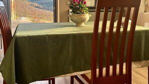 A dining area with a table set for two, a television on the wall, and a view of a vineyard through an open door. - Welcoming accommodation with panoramic views for your stay in Oltrepò Pavese (Torricella Verzate)