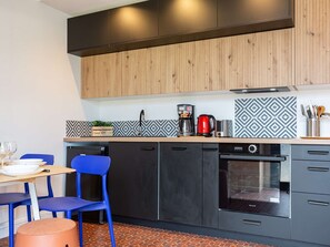 Een moderne keuken met houten kastjes, een zwart aanrecht en een betegelde spatwand.