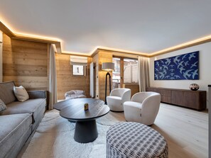 A modern living room with a round table, sofa, and chairs, wooden walls, and a large abstract painting. - Alpine duplex 120 m², 4 bedrooms, fireplace in Val d'Isère (Val-d'Isère)
