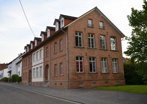 Un grand bĂątiment en briques, dotĂ© de nombreuses fenĂȘtres et dâune entrĂ©e imposante.