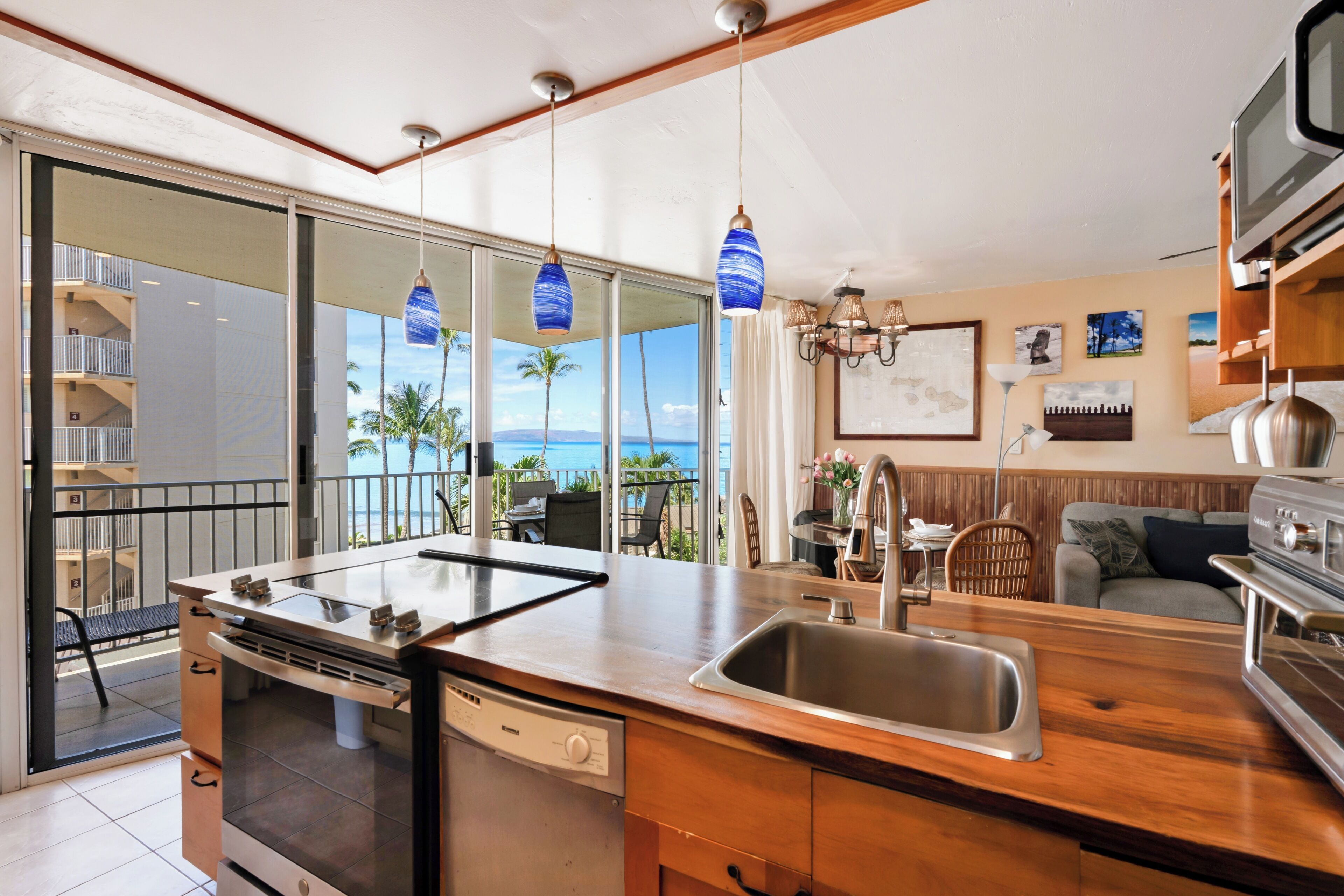 A modern kitchen with a built-in dishwasher, a large island with a sink, and a view of the ocean through large windows.