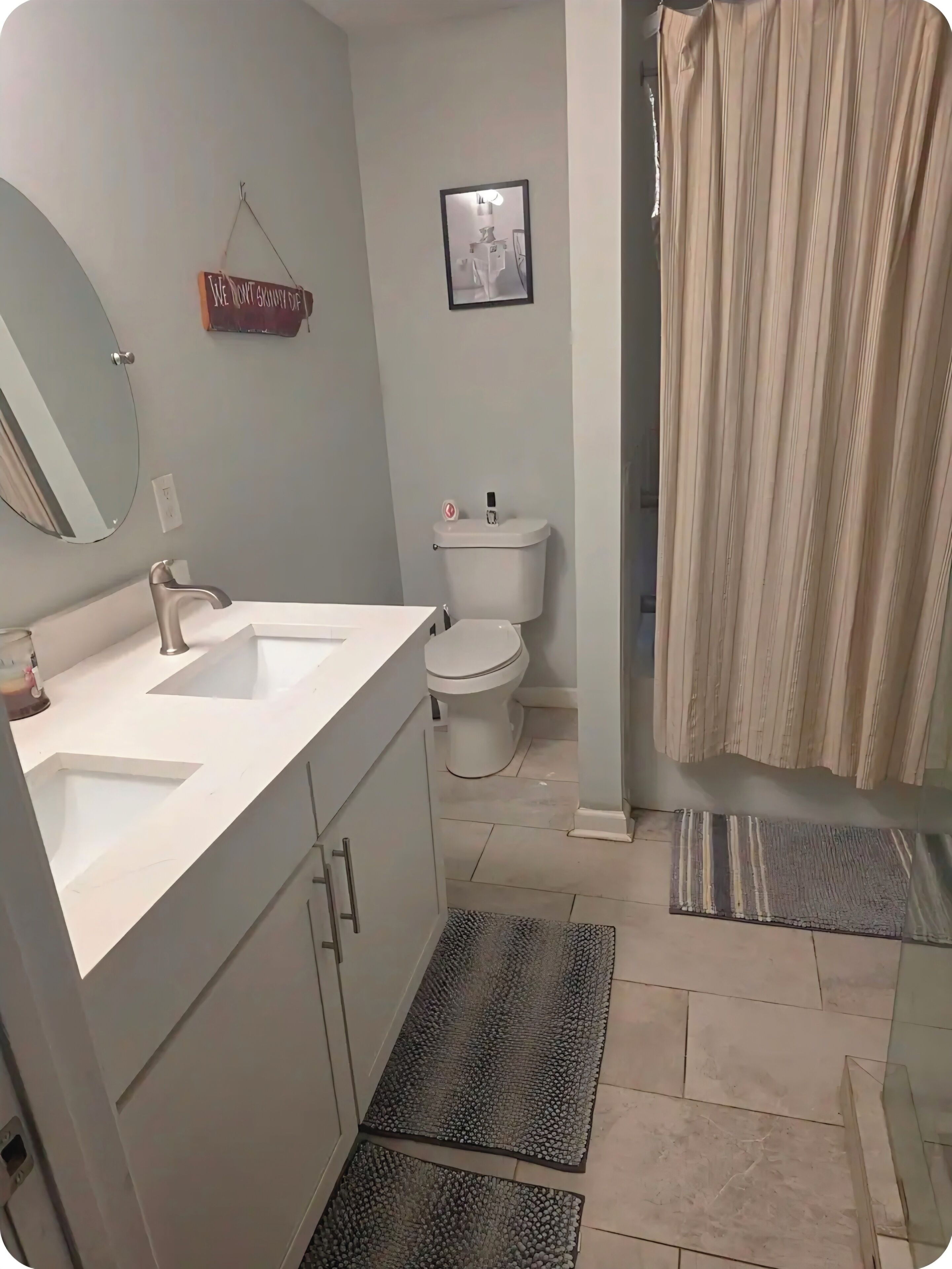 Een badkamer met een witte wastafel, spiegel, toilet en douchegordijn.