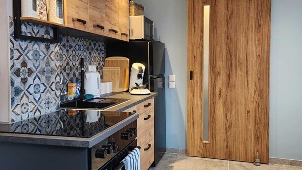 A modern kitchen with wooden cabinets, a black countertop, and a patterned backsplash.