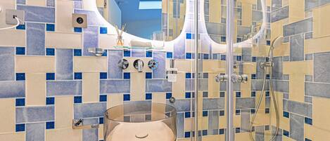 Un baño con un lavabo de vidrio, un espejo y una zona de ducha.