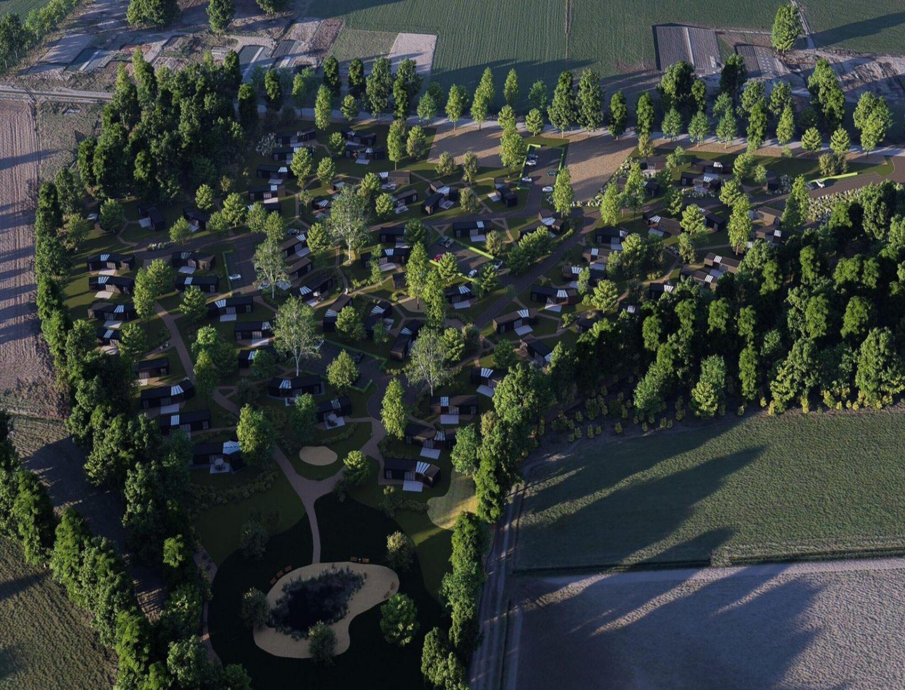 Vista aérea de una zona residencial con varias casas pequeñas, calles y espacios verdes.