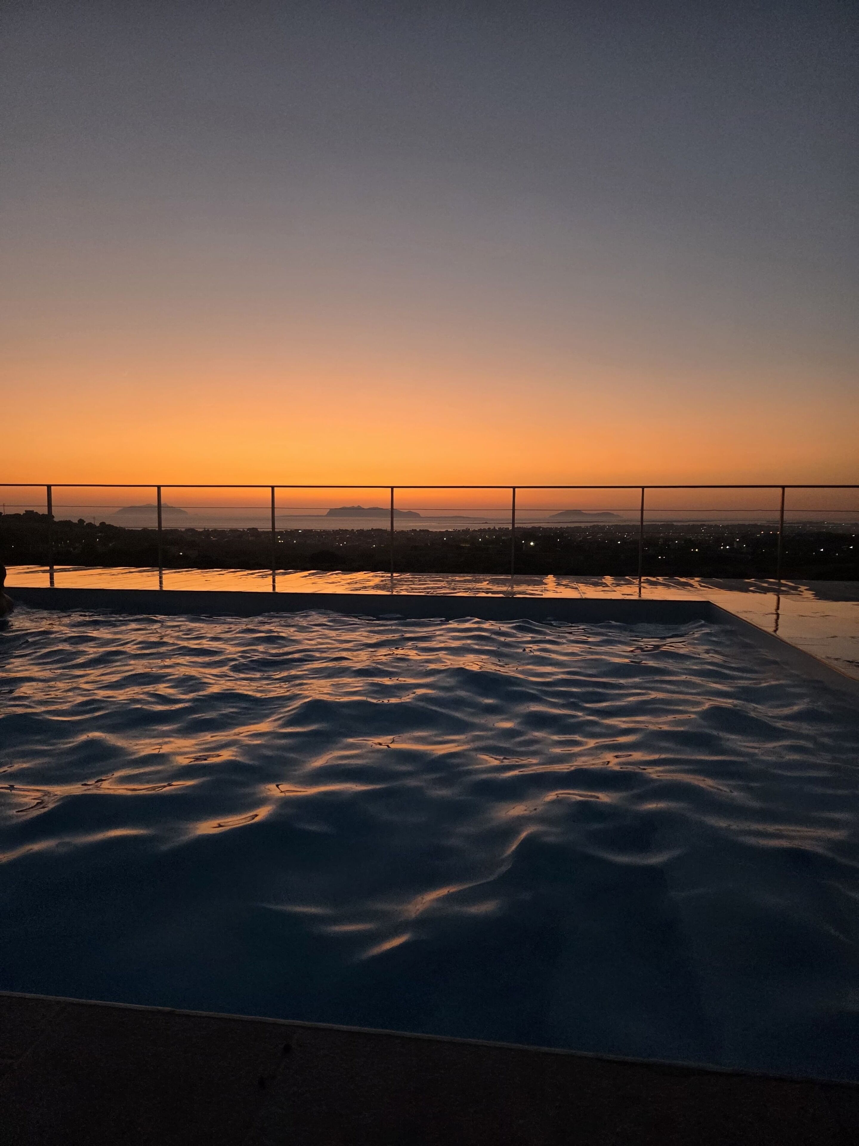 A rooftop pool with a view of the cityscape at sunset.