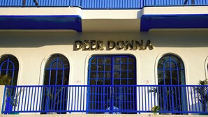 A building with the name "Deer Donna" on the facade, featuring arched windows and a blue railing. - Deer Donna (Belparao)