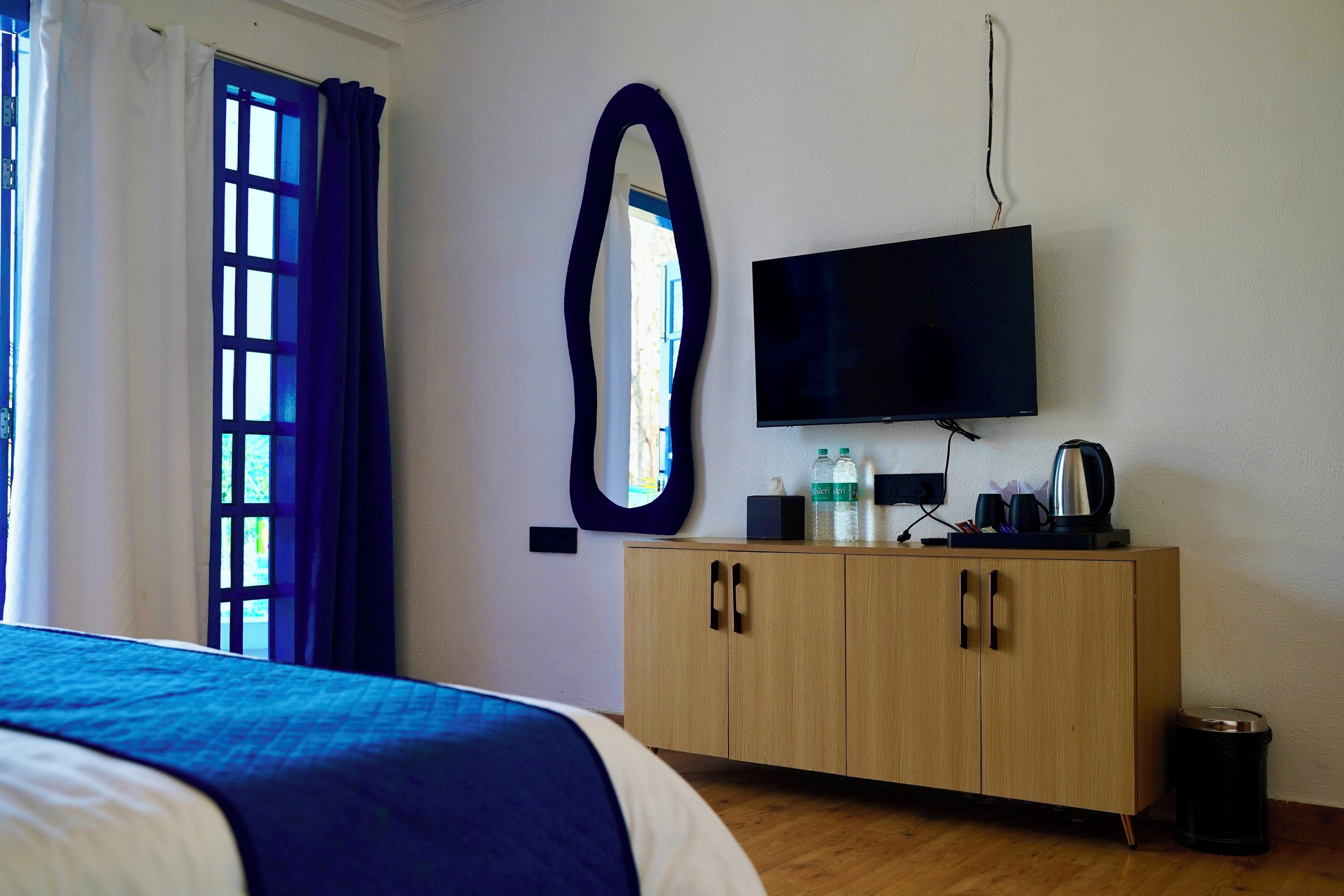 A bedroom with a bed, a wooden cabinet, a television, and a window with curtains.
