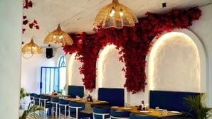 A restaurant with blue booths, white walls, and red foliage decorations. - Deer Donna (Belparao)