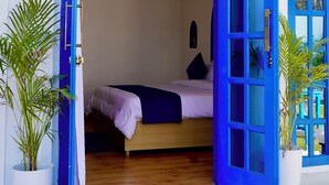 A room with a bed, a blue door, and a potted plant. - Deer Donna (Belparao)