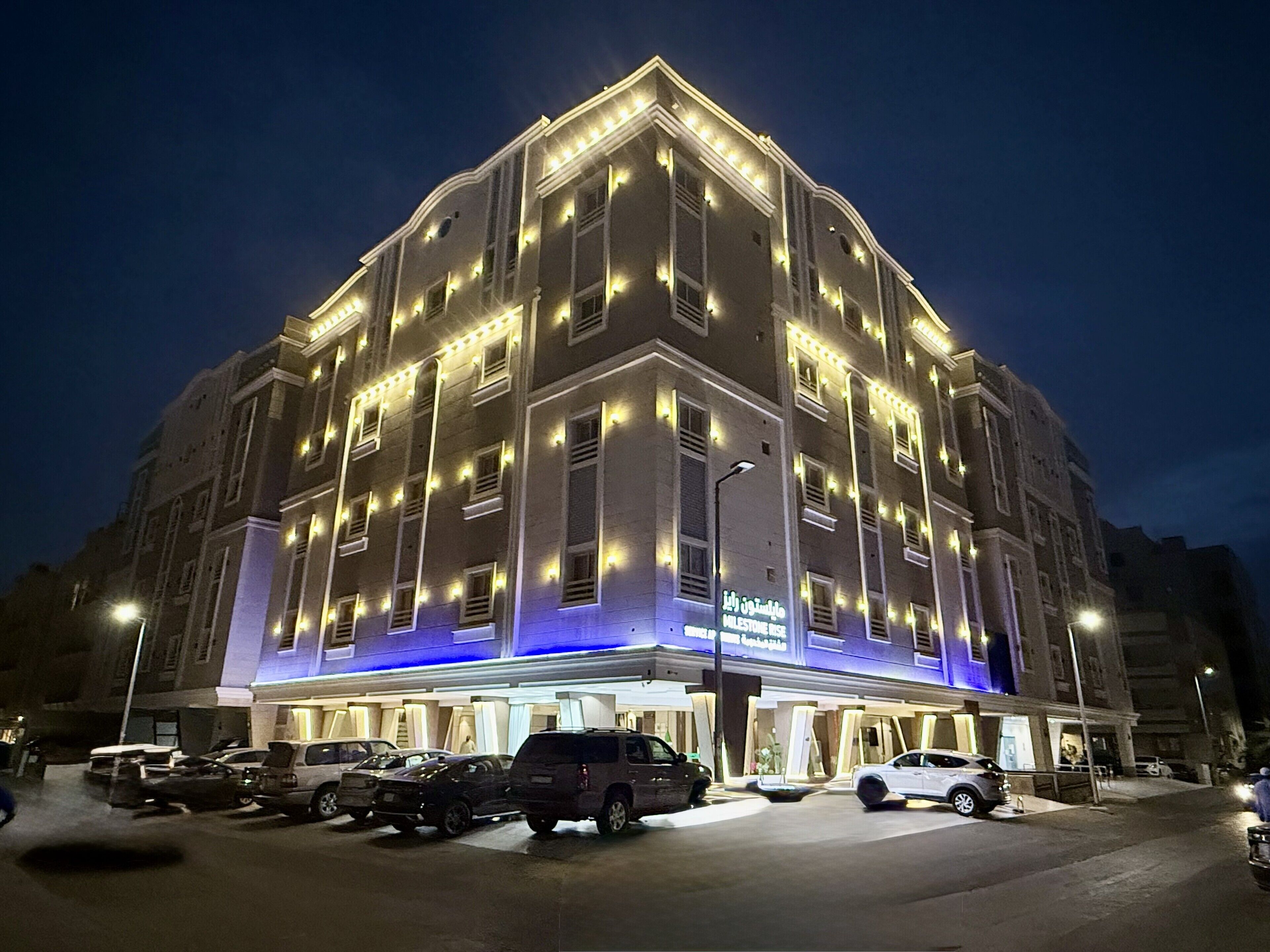 Ett hotell med flera våningar, en modern fasad, upplysta fönster och en väl synlig entré med en skylt.