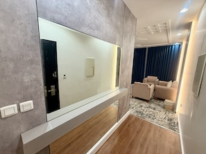 A modern living room with a large mirror, a sofa, and a rug. - Milestone Rise Serviced Apartments (Jeddah)