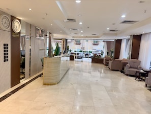 A hotel lobby with a reception desk, seating area, and a view of the street outside. - Milestone Rise Serviced Apartments (Jeddah)