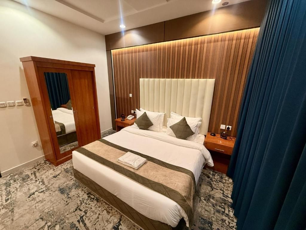 A hotel room with a large bed, a wooden headboard, a nightstand, and a mirror.