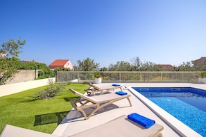 A swimming pool area with lounge chairs and a small lawn. - Beach Villa With Pool Near Split for 8 (Proložac)