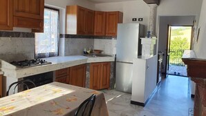 Una cocina con armarios de madera, un refrigerador blanco, una estufa y una mesa de comedor con mantel floreado.