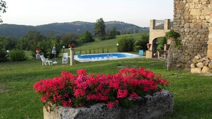 A stone building with a pool, surrounded by greenery and hills. - Il Castelletto di Gomo  (Godiasco)