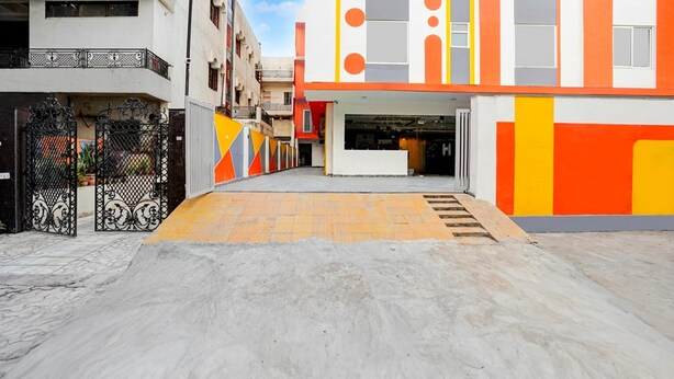 A modern building with a ramp leading to an entrance, a gated area with ornamental ironwork, and a clear sky. - Townhouse Oak Sector 18 Metro Station (Noida)