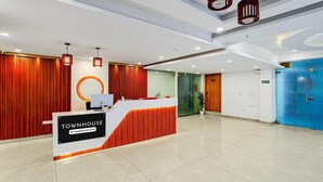 A reception area with a modern design, featuring a reception desk, red curtains, and a blue door. - Townhouse Oak Sector 18 Metro Station (Noida)
