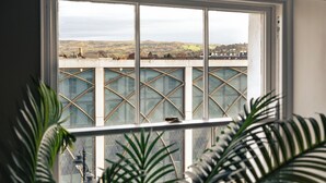 A view through a window with a metal grid design, overlooking a bridge and distant hills. - Stunning High Street Loft in Cheltenham (Cheltenham)