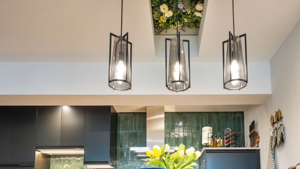A modern kitchen with dark cabinets, a green backsplash, and a hanging light fixture. - Stunning High Street Loft in Cheltenham (Cheltenham)