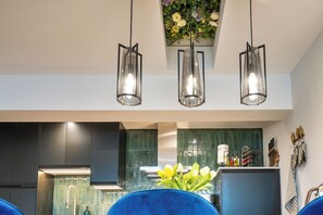 A modern kitchen with dark cabinets, a green backsplash, and a hanging light fixture. - Stunning High Street Loft in Cheltenham (Cheltenham)