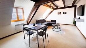 Un moderno apartamento tipo loft con comedor, sofá y televisor montado en la pared.