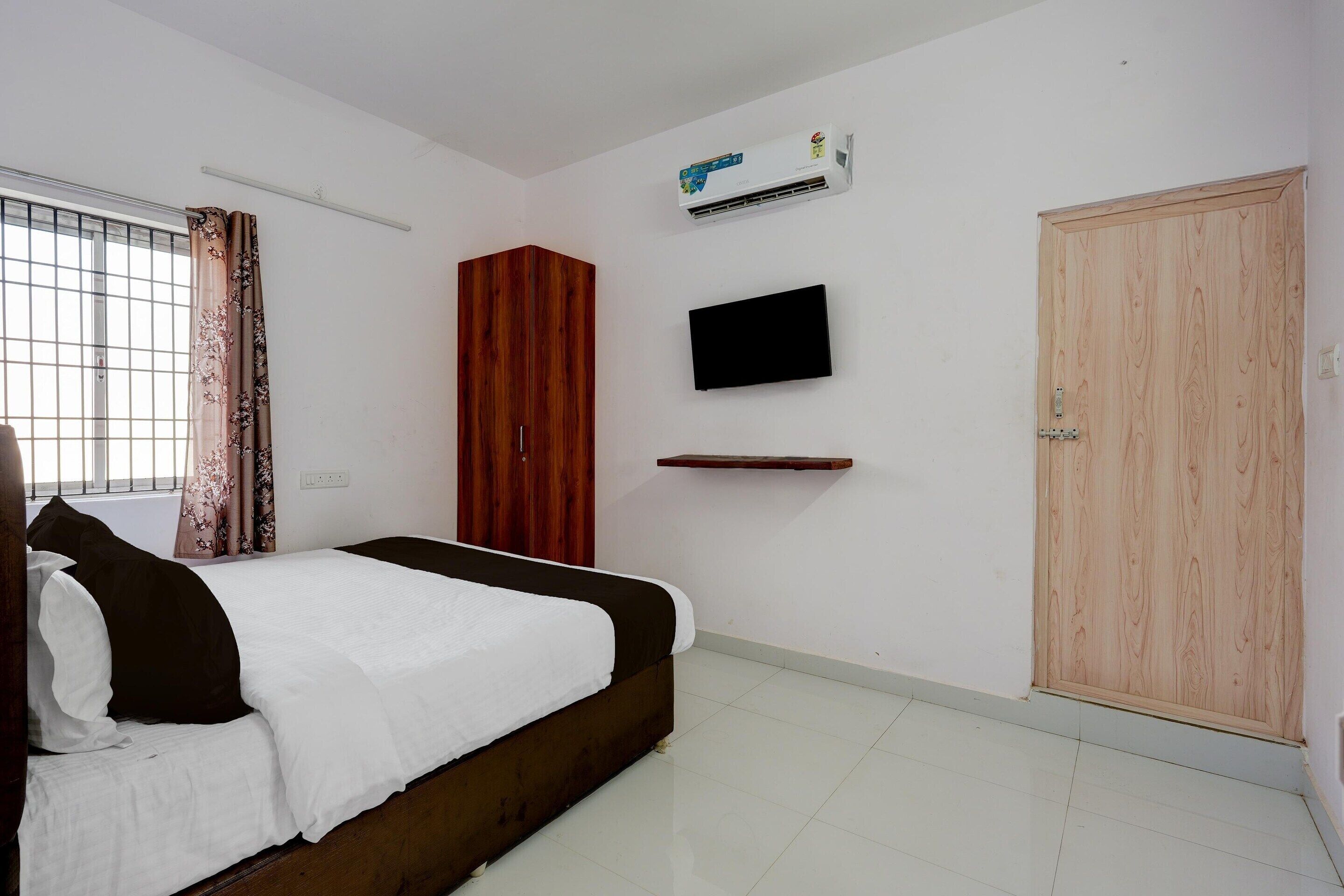 Une chambre à coucher comprenant un lit, une armoire, un téléviseur fixé au mur et un appareil de climatisation.