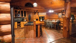 L’intérieur d’une cabane en rondins comprend une cuisine, un coin repas et une cheminée.