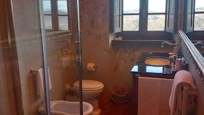 A bathroom with a glass-enclosed shower, a toilet, and a sink.