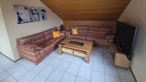 A cozy living room with a patterned sofa set, a wooden coffee table, and a television.