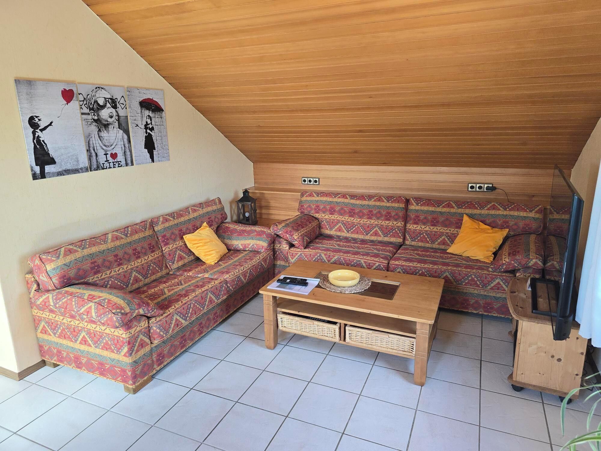 Un salon chaleureux avec un canapé à motifs, une table basse et une œuvre d’art accrochée au mur.