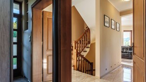 Ein geräumiger Flur mit einer Holztreppe, Blick in einen Wohnbereich und einer Tür zu einem weiteren Zimmer.
