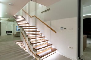 A modern staircase with wooden steps and glass railings, leading to a living area with a flat-screen TV and a sofa. - Grand Party Villa Near Imotski With Jacuzzi (Imotski)