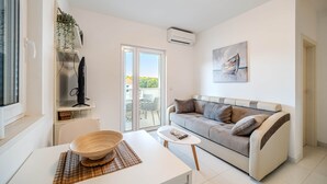 Una sala moderna con un sofá, una mesa de comedor con un tazón, un televisor y una ventana con vistas.