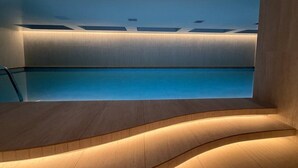 A modern indoor swimming pool with a wooden deck area and recessed lighting. - Suite de diseño en Adagio: terraza, spa y lujo (Quito)