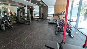 Un gimnasio moderno con diversos equipos de ejercicio, amplias ventanas y un diseño limpio y espacioso.