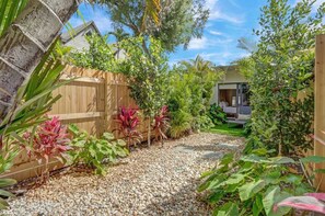 A garden with a gravel path, wooden fence, and various plants. - Open-concept Urban Stay (Fort Lauderdale)