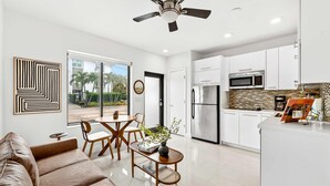 A modern kitchen with white cabinets, stainless steel appliances, and a tiled backsplash. - Sleek Kitchenette Queen Bed (Fort Lauderdale)
