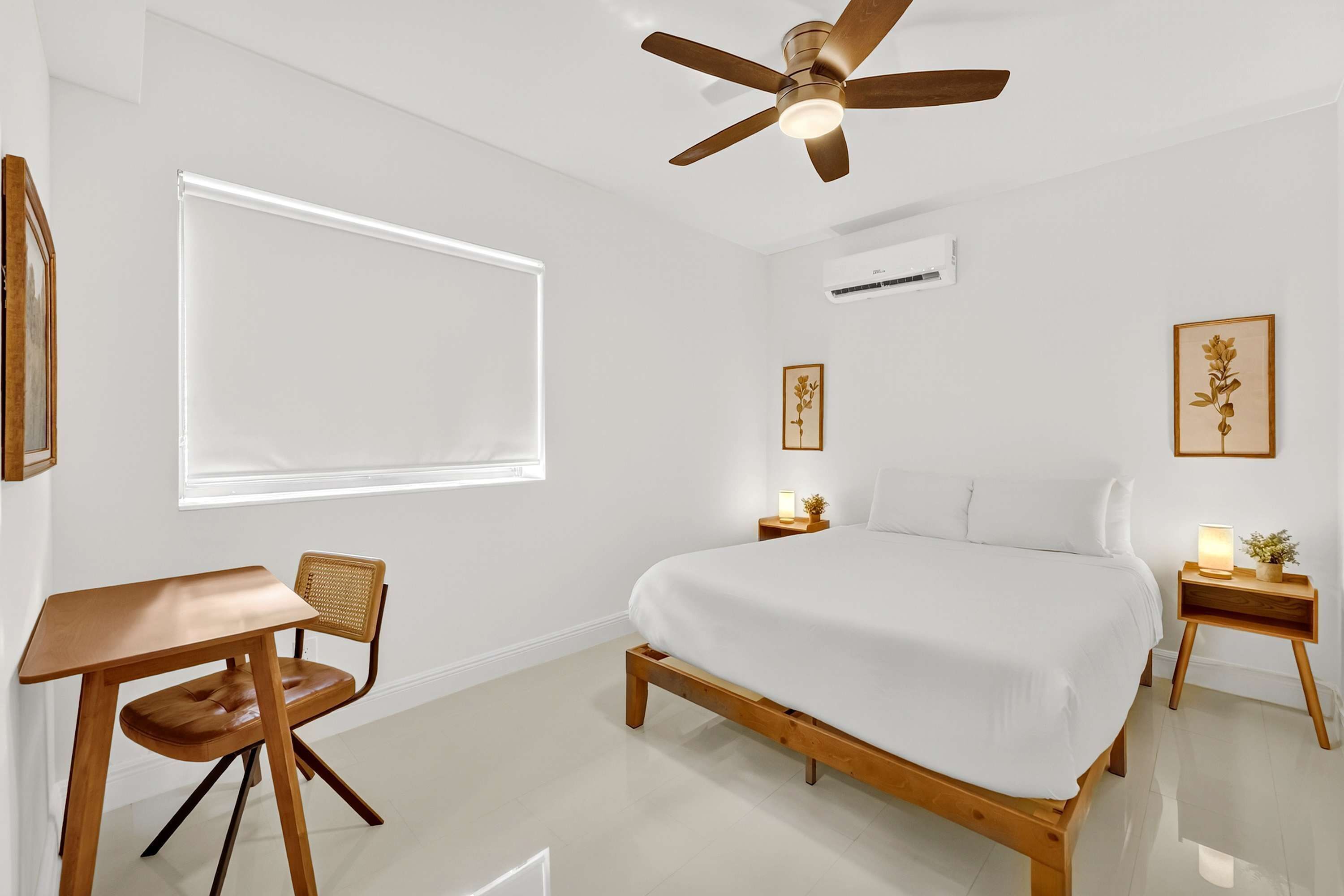 Un dormitorio con cama de madera, un escritorio y una silla. Incluye ventilador de techo, ventana y aire acondicionado instalado en la pared.
