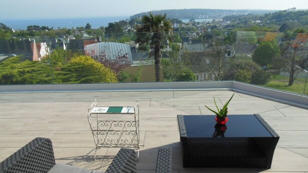 Una terrazza sul tetto con vista sulla città, un tavolino con una pianta e due poltrone da relax.
